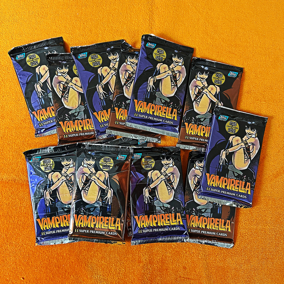 Multiple packs of Vampirella trading cards on an orange background