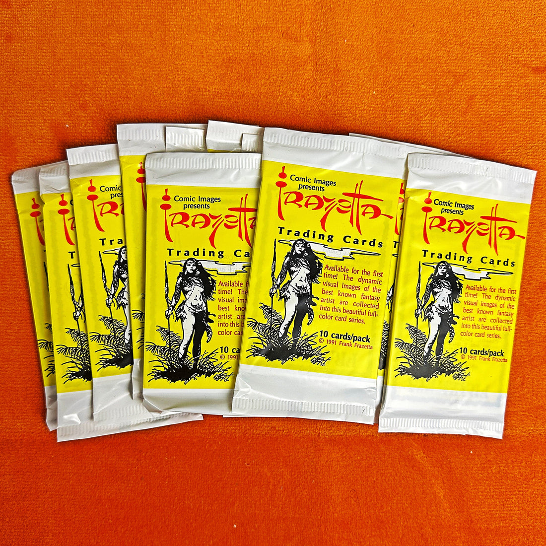 Packets of 'FRAZETTA' trading cards on an orange background
